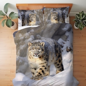 May include: A bedding set featuring a duvet cover and two pillowcases with a photographic print of a snow leopard walking through a snowy, rocky landscape. The leopard has thick, spotted fur and is shown in shades of white, gray, and black.