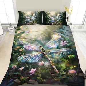 May include: A bedding set featuring a large, iridescent dragonfly with translucent wings centered on a quilt and two matching pillowcases. The design displays a forest scene with soft green foliage, glowing light, and small pink flowers.