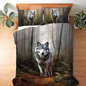 May include: A bedding set featuring a duvet cover and two pillowcases with a printed design of a grey wolf standing in a misty forest. The scene depicts a wolf in the centre of the duvet and one wolf on each pillowcase, surrounded by trees.