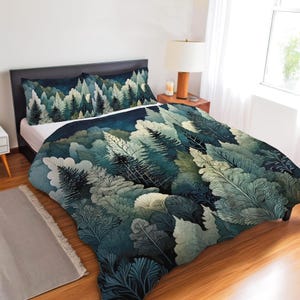 Könnte beinhalten: Ein Bett mit Bettbezug und zwei passenden Kissenbezügen, verziert mit einem dichten Waldmuster in tiefem Petrol, Waldgrün und blassem Salbei. Das Design zeigt geschichtete Nadelbäume vor einem dunklen, sternenklaren Nachthimmel.