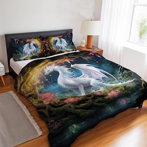May include: A bedding set featuring a white dragon with large wings, set in a fantasy forest scene. The comforter and pillowcases display the dragon amidst pink blossoms and a mystical, glowing backdrop. The set includes a comforter and two pillowcases.
