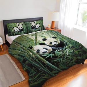 May include: A bedding set featuring a panda bear theme. The set includes a comforter and two pillowcases, all displaying panda bears nestled in bamboo. The color palette is dominated by green and white, creating a natural and serene aesthetic.