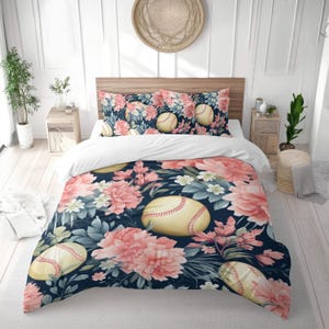 May include: A baseball-themed bedding set featuring a navy blue background with large pink floral and baseballs. The set includes a duvet cover and two pillowcases, creating a cohesive and decorative bedroom ensemble.