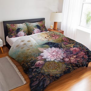 Peut inclure: Une parure de lit composée d'une housse de couette et de deux taies d'oreiller avec un imprimé floral sombre et pictural. Le motif présente de grands dahlias roses et violets, un feuillage complexe et des corbeaux sur fond dégradé.