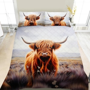 May include: A bedding set featuring a Highland cow design. The set includes a quilt and two pillowcases, all displaying a detailed illustration of a brown and orange cow with long horns. The background shows a field and a cloudy sky.