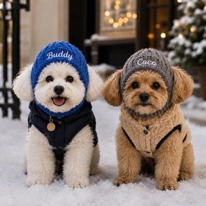 Op de afbeelding: Twee honden dragen gebreide mutsen en vesten. De witte hond draagt een blauwe muts met de naam Buddy in het wit geborduurd en een marineblauw vest. De tan hond draagt een grijze muts met de naam Coco in het wit geborduurd en een beige fleecevest.