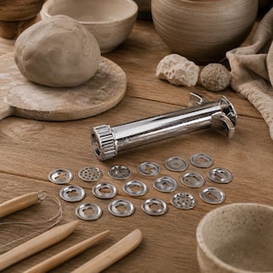 May include: A silver metal clay extruder tool with a cylindrical body and a threaded cap, accompanied by twenty circular metal discs featuring various cutout shapes for shaping clay, alongside wooden sculpting tools and a ball of grey clay.