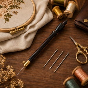 May include: A punch needle tool with a black handle and brass accents, accompanied by three interchangeable metal needles, a wooden embroidery hoop with floral fabric, gold-toned scissors, and several spools of thread on a dark wood surface.