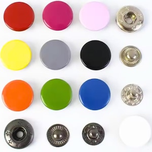 Puede incluir: Una colección de broches de presión coloridos en varios tonos, incluyendo rojo, rosa, amarillo, gris, negro, naranja, verde y azul. La imagen también muestra varios componentes metálicos de broches en plata y gris oscuro.