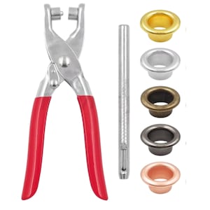 Op de afbeelding: Een metalen oogjeszetter met rode handgrepen, een zilveren ponsgereedschap en een assortiment oogjes in goud, zilver, brons, gunmetal en koperkleuren. Ideaal voor knutsel- en leerbewerkingsprojecten.