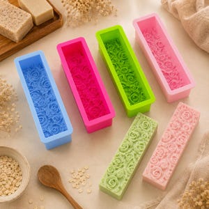 May include: A collection of rectangular silicone molds and finished soap bars featuring intricate rose patterns. The set includes blue, hot pink, lime green, and light pink molds, alongside two soap bars in pale green and light pink with floral designs.