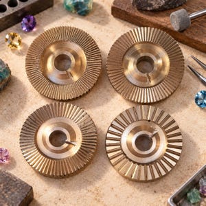 May include: Four circular brass jewellery setting tools with radial grooves and a central hole. Each tool features a small metal pin protruding from the inner edge. These metallic components are arranged in a square formation on a textured surface.