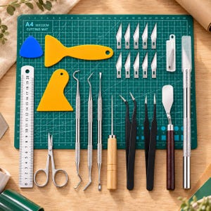 Puede incluir: Un set de herramientas para manualidades con una base de corte verde A4 de 30x22cm, regla metálica, tijeras, espátulas de plástico amarillo, una espátula triangular azul, cuchillas metálicas, punzones, un punzón con mango de madera y pinzas negras.