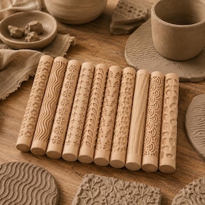 May include: A set of nine cylindrical wooden rolling pins featuring various carved patterns including flowers, waves, snowflakes, stars, leaves, and geometric shapes, arranged side by side on a wooden surface with textured clay pieces.