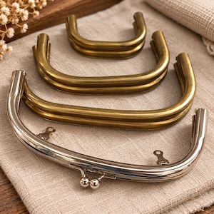 May include: A collection of four U-shaped metal purse frames. Three frames feature a matte antique brass finish, while the largest front frame has a polished silver-tone finish with a double ball clasp closure and two small attachment loops.