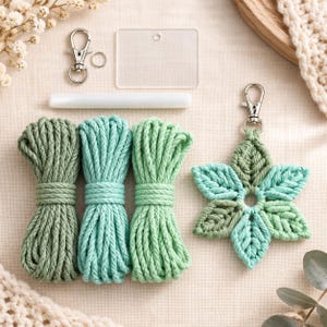 Puede incluir: Un kit de manualidades de macramé que incluye tres ovillos de cuerda de algodón en tonos verde salvia, menta y verde claro, un llavero en forma de estrella, una pieza acrílica rectangular transparente, un mosquetón plateado y una varilla de plástico.