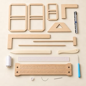 Könnte beinhalten: Ein Set an Buchbindewerkzeugen bestehend aus Holzrahmen, einem Metalllineal, einem Falzbein, einem Holzfalzer, einer Spule mit weißem Garn, einem transparenten Kunststofflineal, einer Holzheftlade, einer weißen Perle sowie einer gebogenen und geraden Nadel.