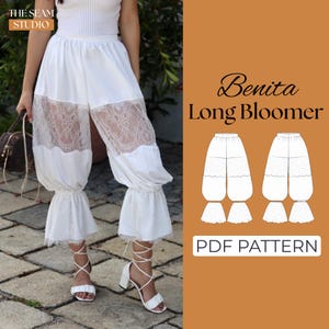 May include: White long bloomers featuring a wide lace panel mid-thigh and ruffled hems. The image includes text reading The Seam Studio, Benita Long Bloomer, and PDF Pattern, alongside a technical line drawing of the garment design.