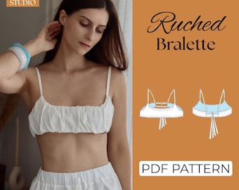 May include: A white ruched bralette PDF pattern by The Seam Studio. The image displays a white crop top with thin straps and gathered fabric, alongside a technical line drawing showing the front and back views with tie-back details.