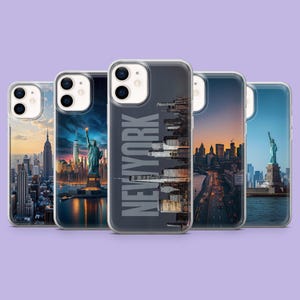 Può includere: Una collezione di cinque custodie per telefono con monumenti iconici di New York City. Ogni custodia mostra un'immagine diversa, tra cui la Statua della Libertà, l'Empire State Building e paesaggi urbani. Il testo "NEW YORK" è stampato verticalmente su una custodia.