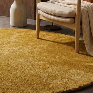 Close up texture of mustard yellow hand tufted wool rug showing dense soft cut pile fibers, premium handmade wool carpet