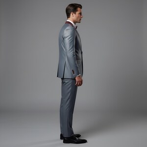 May include: A gray suit with a burgundy lapel and bow tie. The suit has a two-button closure and is paired with black dress shoes. The background is a solid gray.