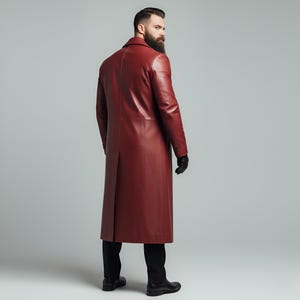 May include: A long, burgundy leather coat with a classic design. The coat features a notched collar, button closures, and a back vent. The person in the image is wearing black gloves and black pants.
