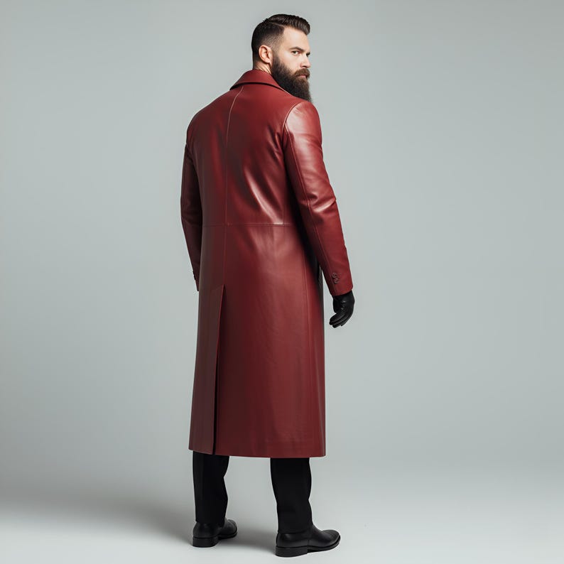 May include: A long, burgundy leather coat with a classic design. The coat features a notched collar, button closures, and a back vent. The person in the image is wearing black gloves and black pants.