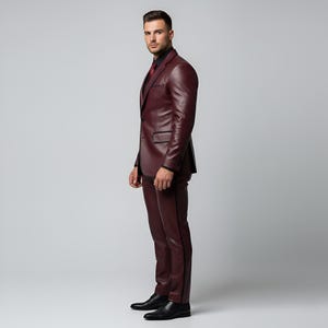 K&ouml;nnte beinhalten: Ein burgunderfarbener Lederanzug mit schwarzem Hemd und roter Krawatte. Der Anzug besteht aus einem Zweiknopf-Blazer und einer passenden Hose mit schwarzem Besatz. Schwarze Lederschuhe vervollst&auml;ndigen das Ensemble. Formelle Kleidung.