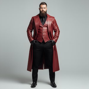 May include: A burgundy leather trench coat, vest, and black pants ensemble. The long coat features a double-breasted design. The outfit is completed with a black tie, gloves, and dress shoes. The model is standing with hands in pockets.