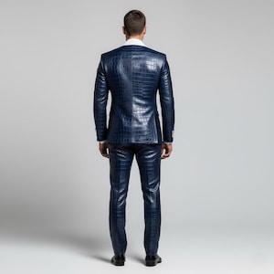 May include: A navy blue suit with a crocodile skin texture. The suit includes a jacket and matching trousers. The jacket has a white collar and the trousers are straight-legged. The person is wearing black shoes.