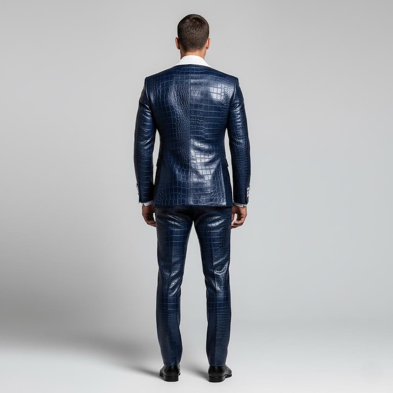 May include: A navy blue suit with a crocodile skin texture. The suit includes a jacket and matching trousers. The jacket has a white collar and the trousers are straight-legged. The person is wearing black shoes.