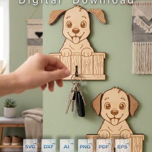 May include: A digital download featuring a laser-cut wooden wall-mounted key holder shaped like a puppy peeking over a fence. The design includes a hook for keys and is available in SVG, DXF, AI, PNG, PDF, and EPS file formats for crafting.