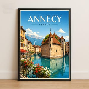 Puede incluir: Un póster de viaje enmarcado con el texto ANNECY FRANCE. La ilustración muestra un edificio de piedra con techo rojo situado en un canal, rodeado de edificios coloridos, flores en una barandilla de metal negro y montañas bajo un cielo azul.