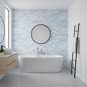 Puede incluir: Un baño moderno con una bañera blanca de forma ovalada. La pared detrás de la bañera presenta un papel pintado con un patrón de olas azules y blancas. Un espejo con marco negro cuelga sobre la bañera. Un toallero negro se apoya en la pared.
