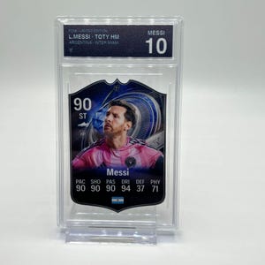 Puede incluir: Una tarjeta coleccionable de Messi calificada. La tarjeta presenta una foto de Messi con una camiseta rosa. La tarjeta está dentro de un soporte de plástico transparente. La tarjeta tiene el texto "Messi 10" y "90 ST". La tarjeta también tiene el texto "PAC SHO PAS DRI DEF PHY 90 90 90 94 37 71".