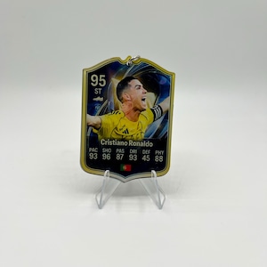 May include: A rectangular acrylic collectible card featuring a portrait of Cristiano Ronaldo in a yellow jersey. The card displays a 95 overall rating, the text Cristiano Ronaldo, and player statistics including PAC 93, SHO 96, PAS 87, DRI 93, DEF 45, PHY 88, with a small Portuguese flag icon.