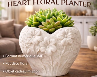 Op de afbeelding: Een witte, hartvormige bloempot met reliëf bloemdetails, met een groene vetplant. De bloempot heeft de tekst "...3D PRINTABLE... HEART FLORAL PLANTER" en "3MF STL Digital Download".