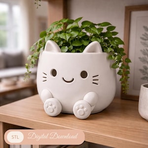 May include: A white ceramic cat-shaped planter with a smiling face, ears, and paws. The planter holds a green leafy plant. The text "Digital Download" is on a pinkish-beige banner at the bottom.