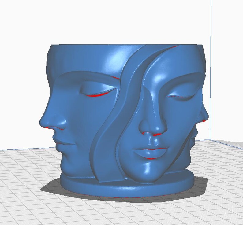 May include: A blue decorative planter featuring three stylized faces with closed eyes. The faces are sculpted in a continuous, flowing design, creating a unique and artistic aesthetic. The planter has a round base.
