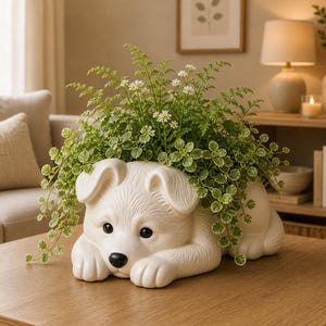 May include: A white ceramic dog-shaped planter filled with green and white leafy plants and small white flowers. The dog planter has black eyes and a black nose, resting on a wooden table. The overall theme is home decor.