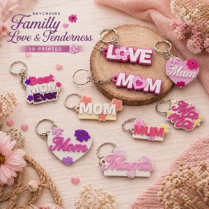 May include: A collection of 3D-printed keychains with the words "Love", "Mom", "Mum", and "Mama" in pink and white. Some keychains are heart-shaped or floral, with the text "Best Mom Ever".