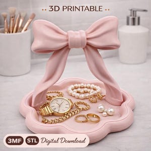 Peut inclure: Un plateau à bijoux rose en forme de nœud papillon contenant une montre en or, des bracelets, des bagues et des perles. Le plateau est décoré d'un nœud et du texte ".. 3D PRINTABLE .." et "Digital Download".