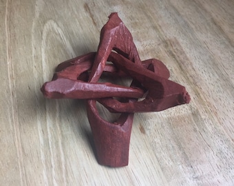 May include: A red wooden stand with a star shape, made of interwoven branches. The stand is perfect for displaying small objects like crystals or figurines.