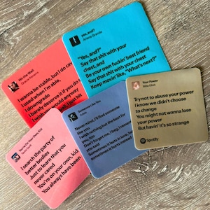 May include: A collection of colorful square coasters with song lyrics and artist names printed on them. The coasters feature songs by Ariana Grande, Gracie Abrams, Taylor Swift, Adele, and Billie Eilish. The Spotify logo is visible.