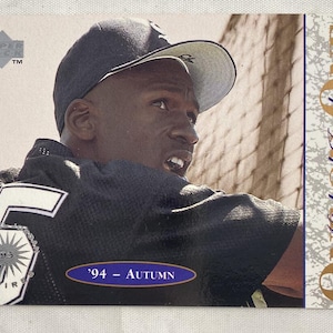 May include: A Michael Jordan Upper Deck trading card. The card features a portrait of Michael Jordan wearing a black jersey with the number 45 and a baseball cap. The card has the text "'94 - Autumn" and "ONE" on the right side.