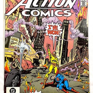 May include: Action Comics #543 comic book cover featuring Superman defeated by Neutron. The cover art shows a yellow-suited Neutron standing over Superman in a city engulfed in flames. Text includes "I've Won!" and "He's Back!"
