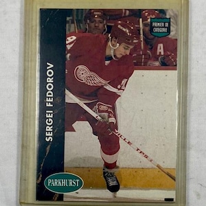 May include: A hockey trading card featuring Sergei Fedorov in a red Detroit Red Wings jersey. The card has the Parkhurst logo and text that reads "Premier de Categorie". The player is holding a hockey stick on the ice.