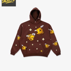 May include: Brown hooded sweatshirt with a pixelated bee pattern. The sweatshirt features a front pocket and a drawstring hood. The brand logo "RALPH JACKET" is in the upper left corner. The bees are yellow and brown.