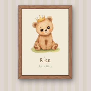 May include: A framed print featuring a watercolor illustration of a teddy bear wearing a gold crown. The bear is sitting on green grass. The name "Rian" and the text "-Little King-" are below the bear.